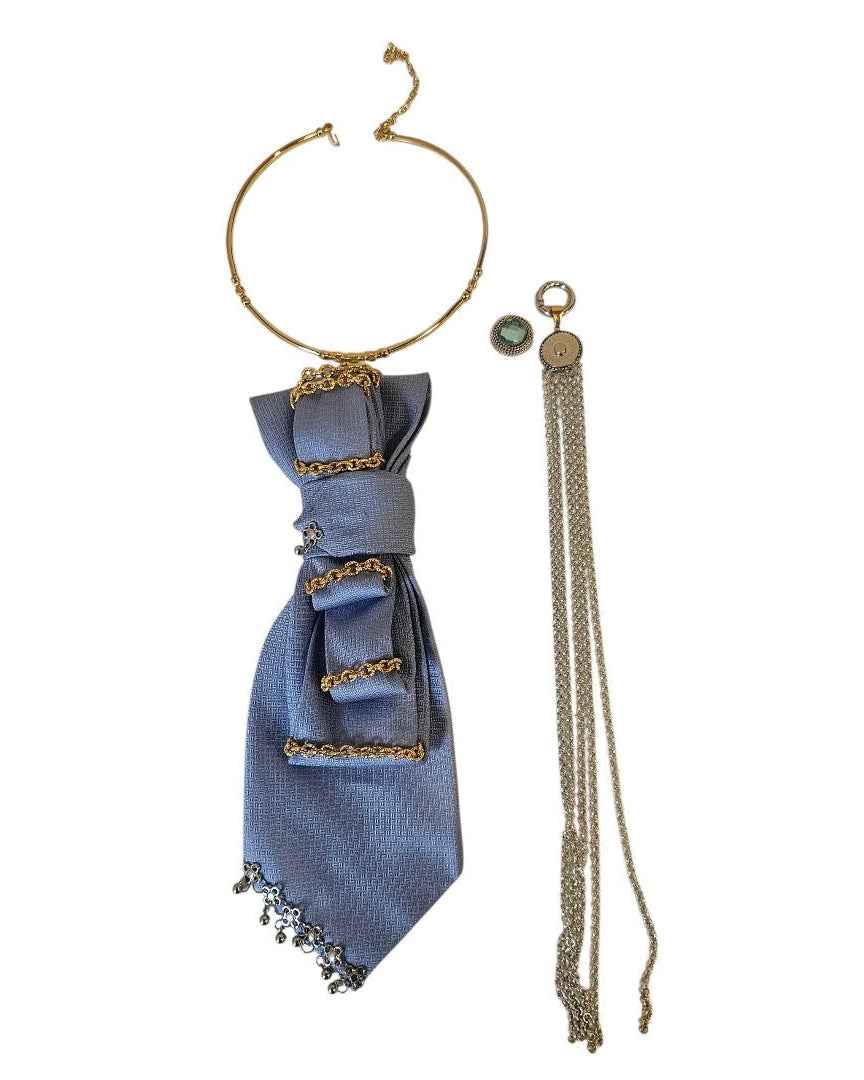 Flat lay cravatta gioiello Marea con pendente Medusa, collarino rigido e elementi modulari su fondo bianco ispirato al Mediterraneo